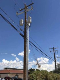 A telephone pole with power lines and wiresDescription automatically generated